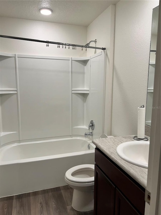 full bathroom featuring wood-type flooring, a textured ceiling, toilet, vanity, and tub / shower combination