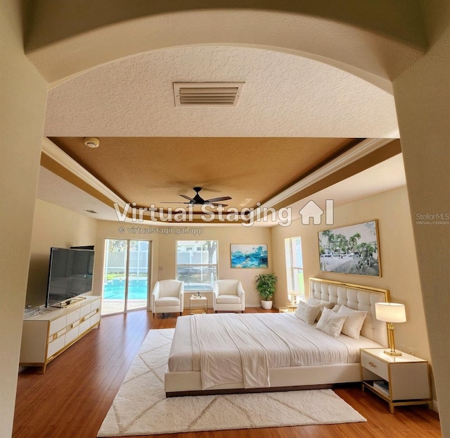 bedroom featuring ceiling fan, light hardwood / wood-style flooring, a tray ceiling, a textured ceiling, and access to outside