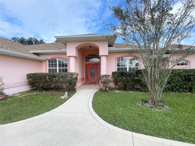 23 Flemington Ln, Palm Coast, FL 32137 - property entrance with a yard, stucco siding, and a shingled roof
