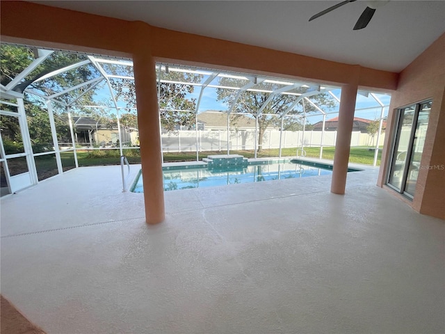 view of swimming pool featuring glass enclosure, ceiling fan, and a patio area