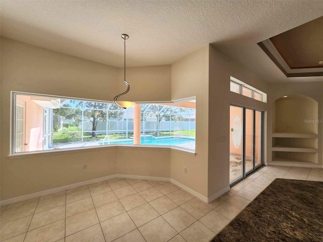 unfurnished dining area with light tile patterned flooring and a textured ceiling