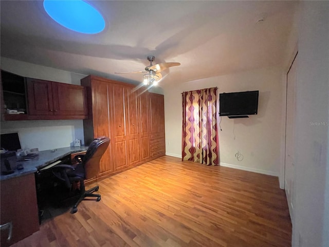 office space with built in desk, light hardwood / wood-style floors, and ceiling fan