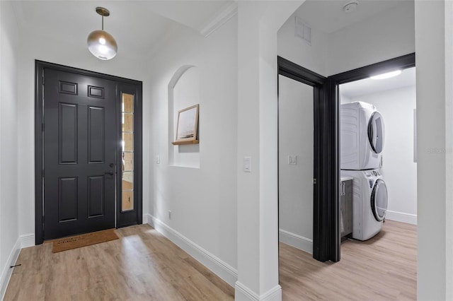 entryway with stacked washer and dryer, ornamental molding, and light hardwood / wood-style flooring