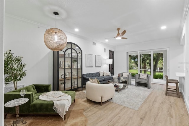 living room with ceiling fan, wood-type flooring, and ornamental molding