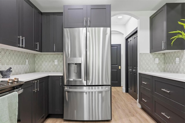 kitchen with decorative backsplash, light countertops, stainless steel fridge with ice dispenser, and light wood finished floors