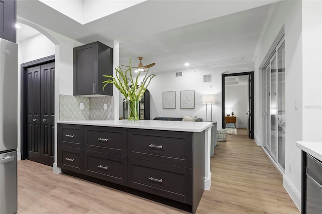 kitchen featuring tasteful backsplash, light countertops, a peninsula, freestanding refrigerator, and light wood-style floors