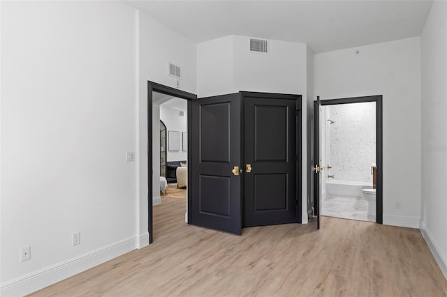 unfurnished bedroom featuring light wood-type flooring and ensuite bathroom