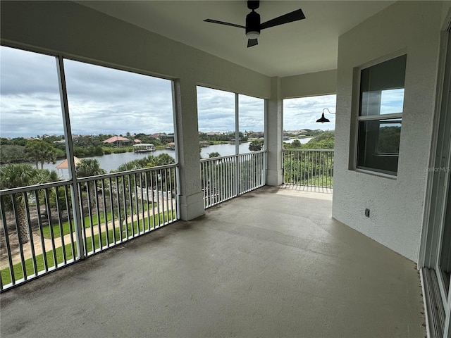 unfurnished sunroom featuring a water view and ceiling fan