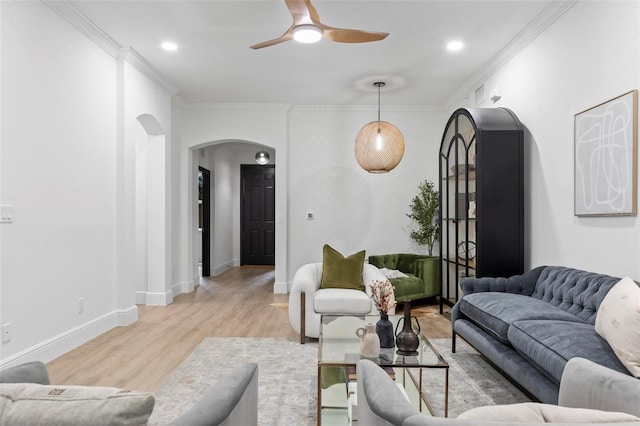 living room with arched walkways, light wood finished floors, crown molding, and baseboards