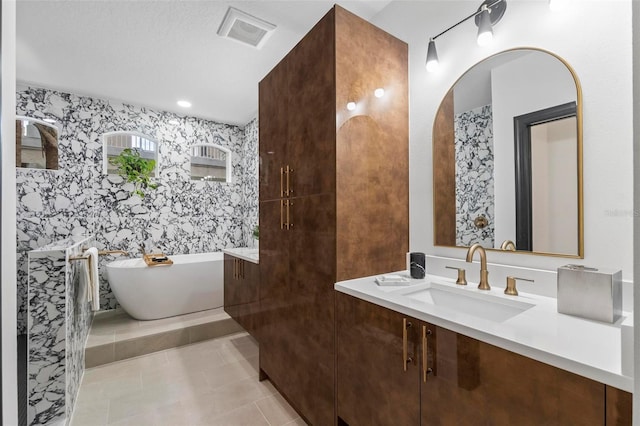 bathroom with vanity, a textured ceiling, tile patterned floors, and a washtub