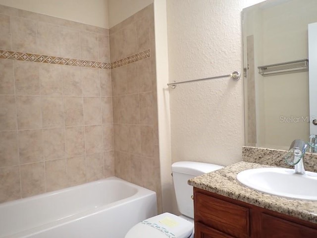 full bathroom with tiled shower / bath, toilet, and vanity