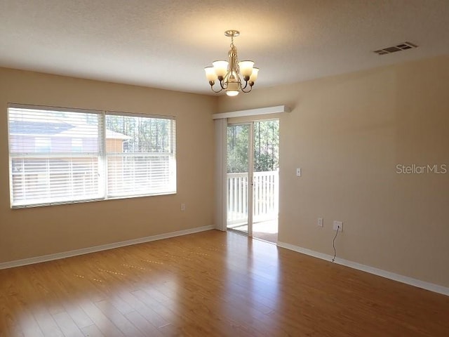 empty room featuring a chandelier and wood-type flooring