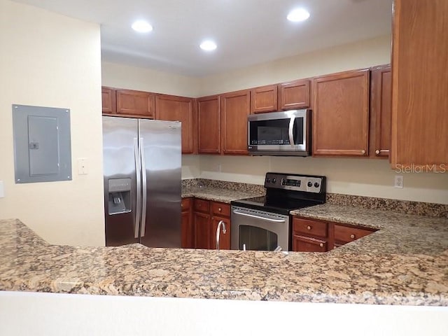 kitchen featuring stainless steel appliances, kitchen peninsula, light stone countertops, and electric panel