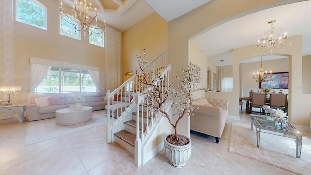 living area featuring arched walkways, a towering ceiling, stairway, tile patterned flooring, and a chandelier