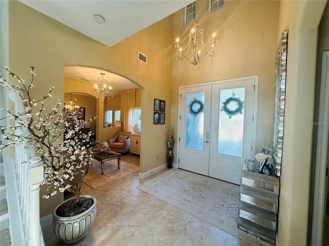 foyer entrance featuring tile patterned flooring, french doors, a high ceiling, and a chandelier