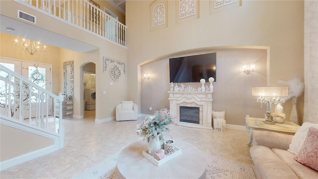 living area featuring arched walkways, visible vents, baseboards, stairs, and a glass covered fireplace