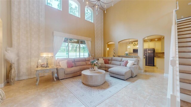 living room featuring a chandelier, light tile patterned floors, and a towering ceiling