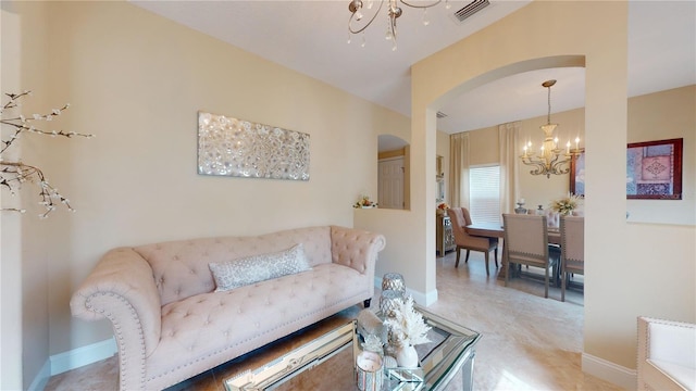 tiled living room with baseboards, visible vents, arched walkways, and a notable chandelier