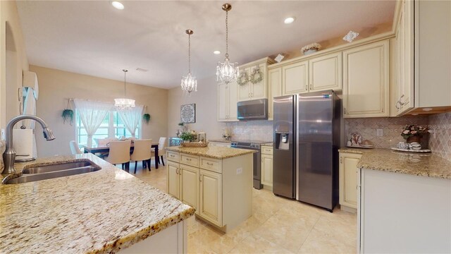 kitchen with appliances with stainless steel finishes, decorative light fixtures, tasteful backsplash, sink, and cream cabinets