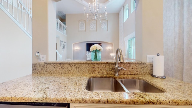 interior space featuring light stone counters, a sink, dishwasher, and an inviting chandelier