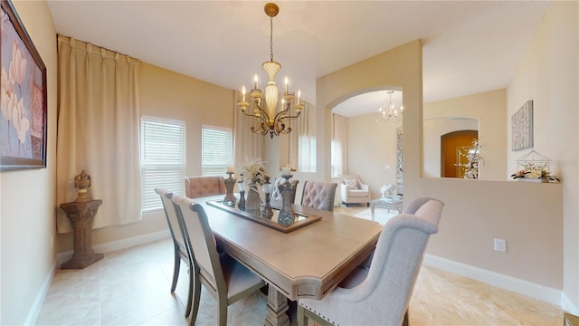 dining room with a chandelier, arched walkways, and baseboards