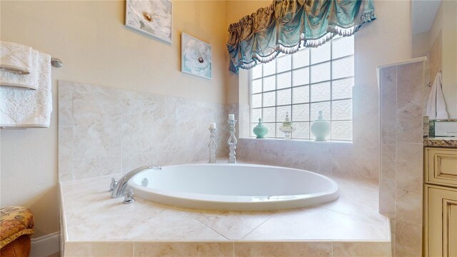 bathroom featuring tiled tub and vanity