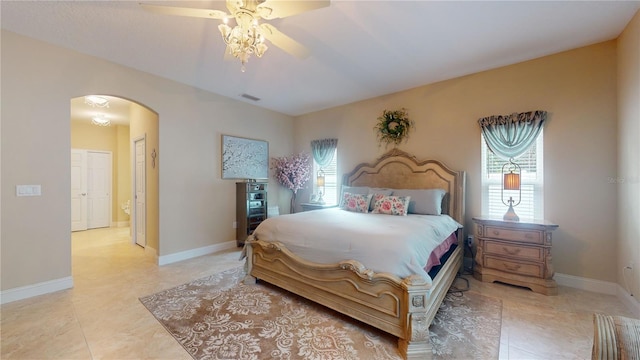 bedroom featuring a ceiling fan, visible vents, arched walkways, and baseboards