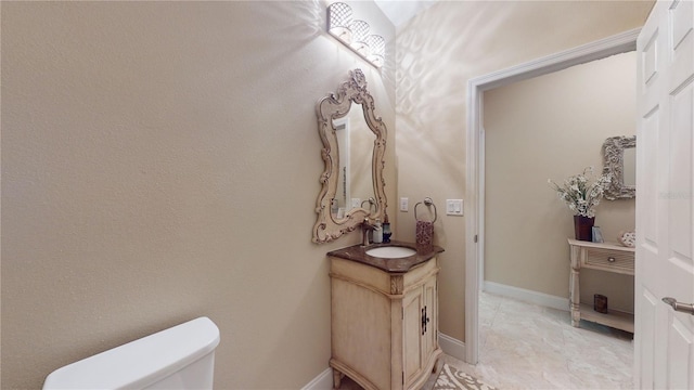 bathroom with vanity, toilet, and baseboards