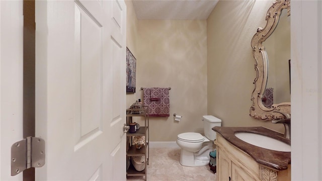 bathroom featuring tile patterned floors, vanity, toilet, and baseboards