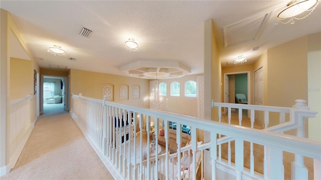 corridor featuring carpet, wainscoting, visible vents, and a textured ceiling