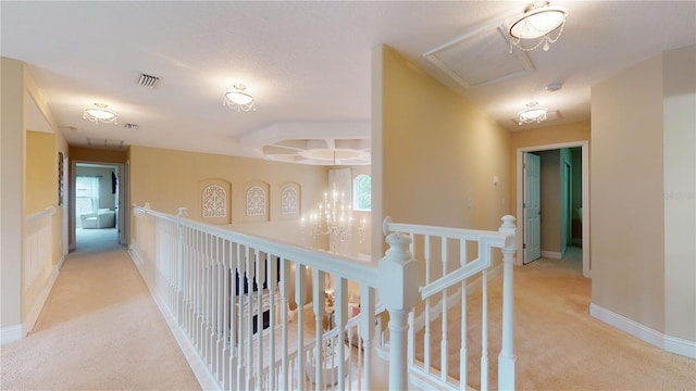 hall with baseboards, light colored carpet, visible vents, and an upstairs landing