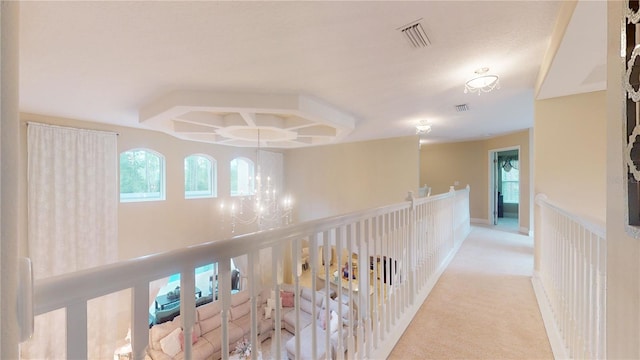 corridor featuring carpet, visible vents, baseboards, and an inviting chandelier