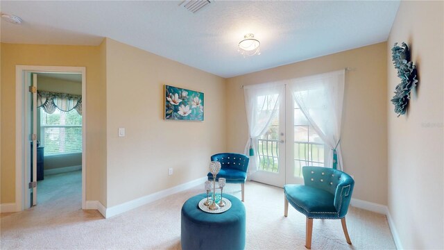 living area featuring light colored carpet and french doors