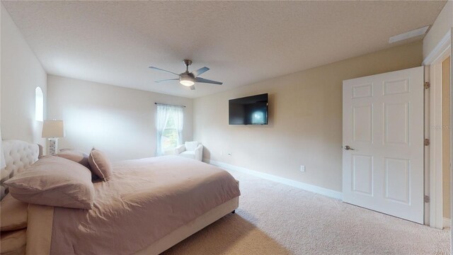 carpeted bedroom with ceiling fan and a textured ceiling