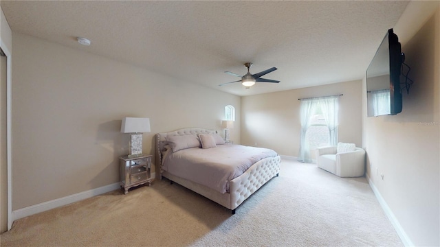 bedroom with ceiling fan, baseboards, a textured ceiling, and light colored carpet