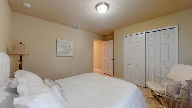 carpeted bedroom with a closet and a textured ceiling