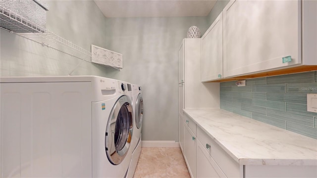 laundry room with light tile patterned floors, washer and clothes dryer, and cabinets