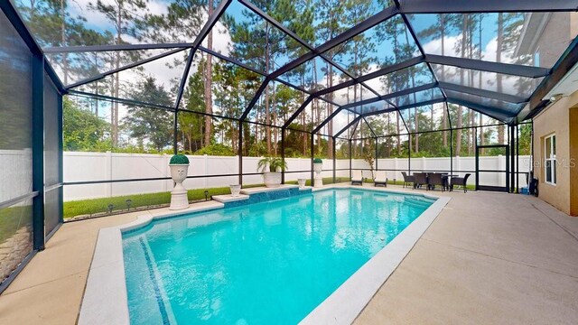 view of pool with glass enclosure and a patio