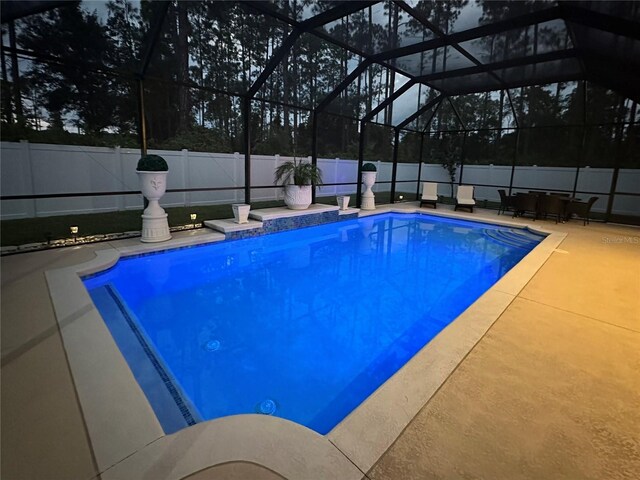 view of swimming pool featuring glass enclosure and a patio area