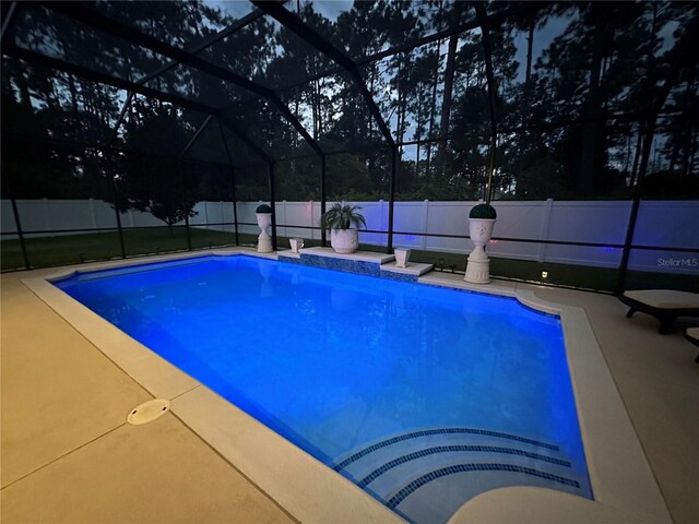 view of swimming pool featuring glass enclosure and a patio area