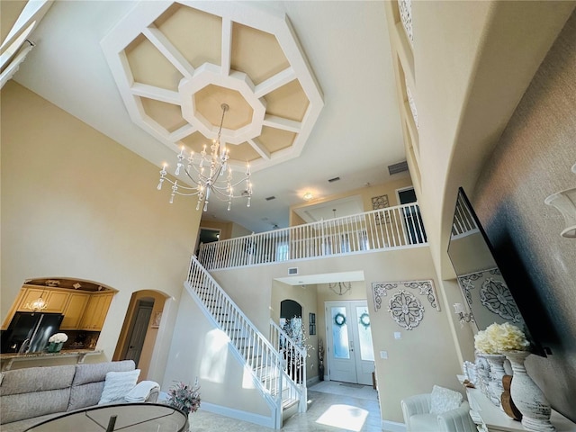 interior space featuring arched walkways, coffered ceiling, a towering ceiling, french doors, and a notable chandelier