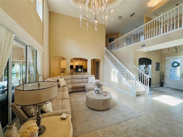 living room with visible vents, arched walkways, baseboards, stairway, and a notable chandelier