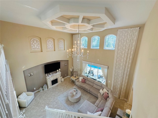 living room featuring a notable chandelier, a fireplace, a high ceiling, coffered ceiling, and baseboards