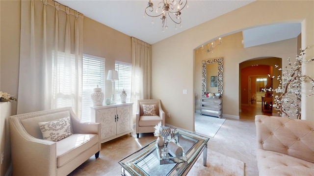 living area featuring arched walkways, light tile patterned flooring, baseboards, and an inviting chandelier