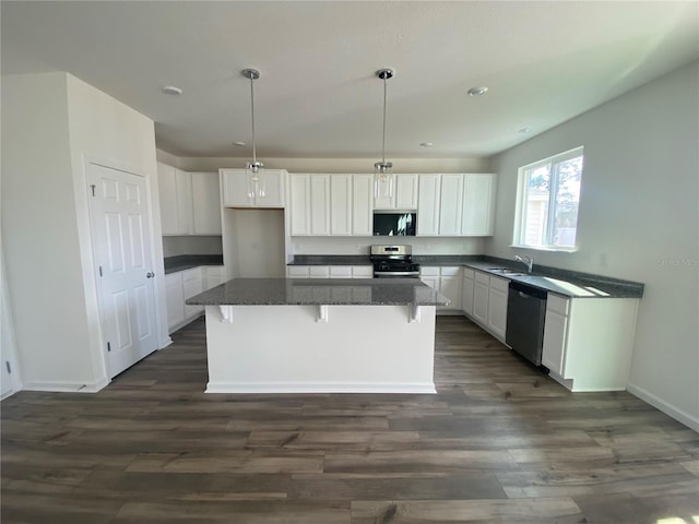 kitchen with white cabinetry, stainless steel appliances, dark hardwood / wood-style floors, decorative light fixtures, and a kitchen island