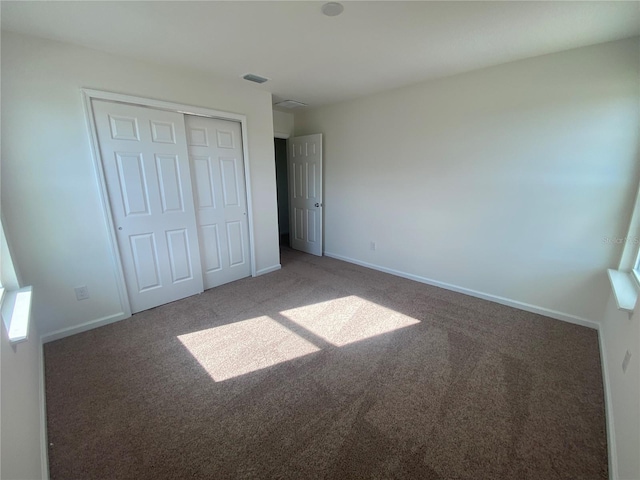 unfurnished bedroom featuring a closet and dark colored carpet