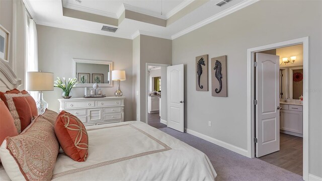 bedroom with crown molding, a raised ceiling, wood-type flooring, and ensuite bathroom