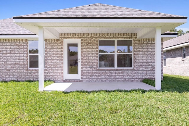 exterior space featuring a yard, brick siding, and roof with shingles