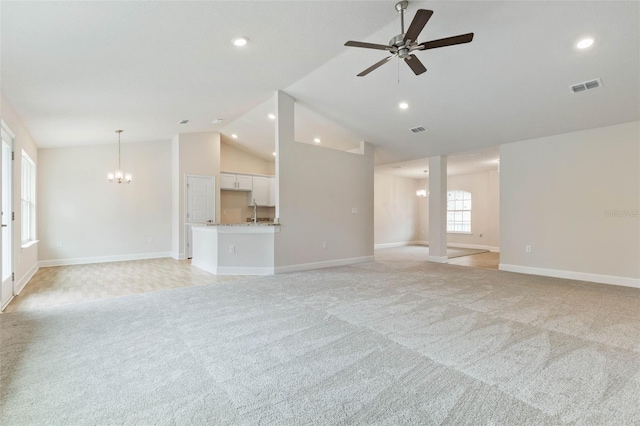 unfurnished living room with sink, high vaulted ceiling, ceiling fan with notable chandelier, and light carpet