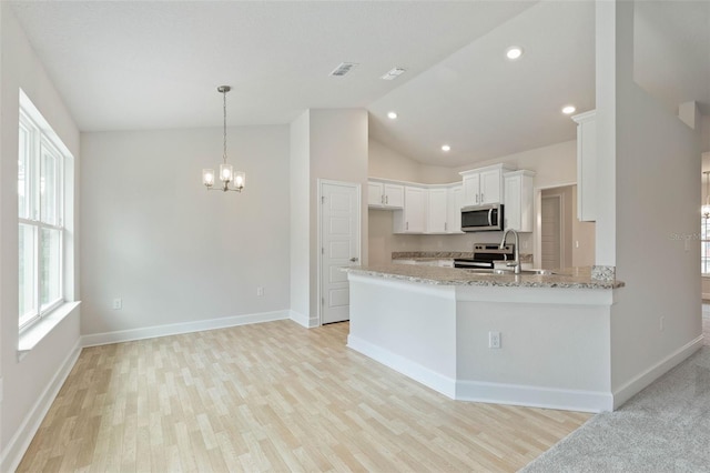 kitchen with light wood-type flooring, light stone countertops, stainless steel appliances, kitchen peninsula, and white cabinets